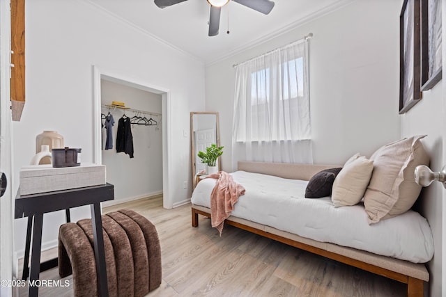 bedroom featuring light wood finished floors, a ceiling fan, baseboards, and crown molding