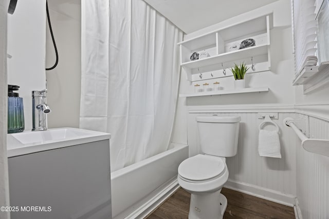 bathroom featuring a sink, shower / bathtub combination with curtain, toilet, and wood finished floors