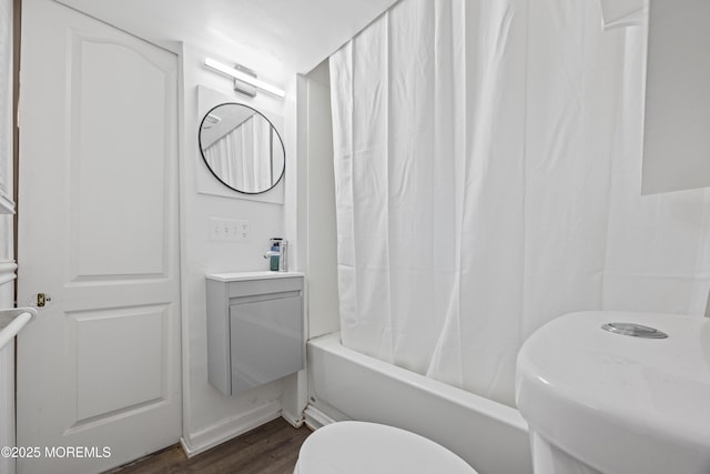 bathroom featuring toilet, a sink, shower / bath combination with curtain, and wood finished floors