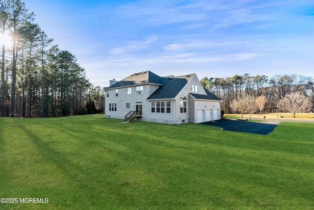 rear view of property with a garage, driveway, crawl space, and a lawn