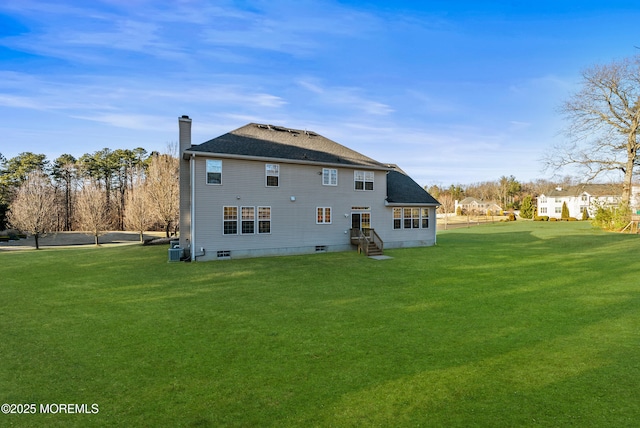 rear view of property with entry steps, central AC unit, a shingled roof, a yard, and a chimney