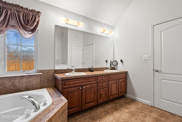 bathroom with lofted ceiling, a relaxing tiled tub, double vanity, and a sink