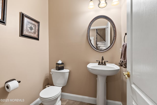 half bathroom featuring toilet and baseboards