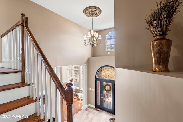 foyer with light wood-style flooring, a notable chandelier, a high ceiling, baseboards, and stairway