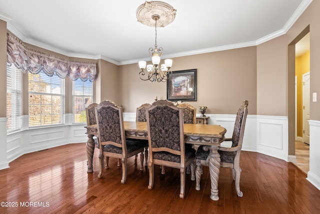 dining space with visible vents, wainscoting, wood-type flooring, ornamental molding, and an inviting chandelier