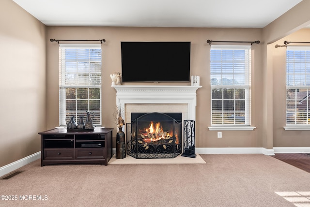 living room with baseboards, a lit fireplace, and a healthy amount of sunlight