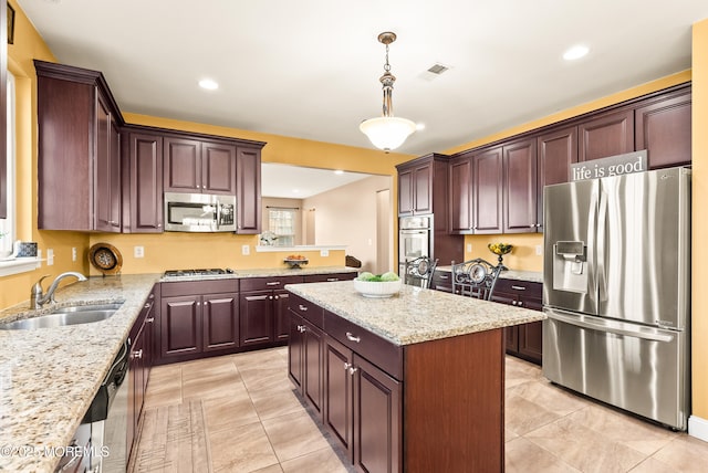 kitchen with visible vents, a kitchen island, appliances with stainless steel finishes, hanging light fixtures, and a sink