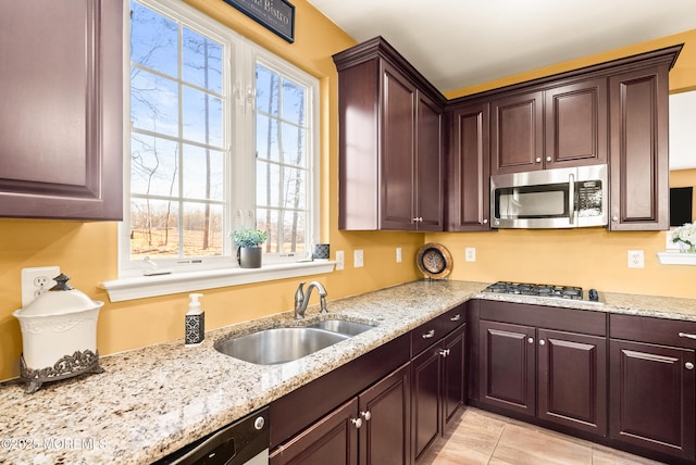 kitchen with stainless steel appliances, plenty of natural light, a sink, and light stone counters