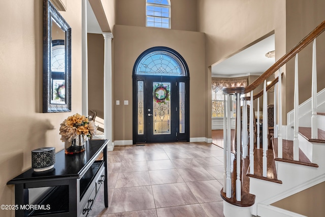 foyer entrance featuring a healthy amount of sunlight, ornate columns, a high ceiling, and stairway