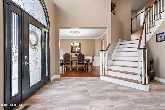 foyer featuring a chandelier, crown molding, stairway, and a high ceiling