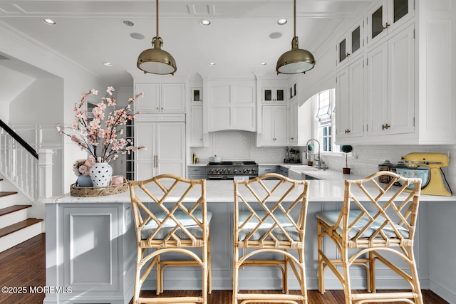 kitchen featuring white cabinets, range with two ovens, glass insert cabinets, premium range hood, and a sink