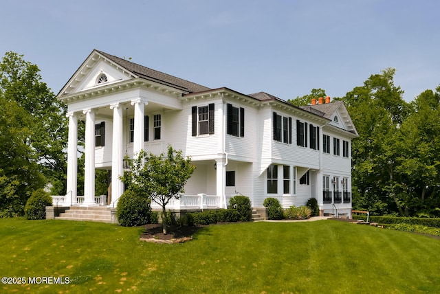 rear view of house with covered porch and a lawn