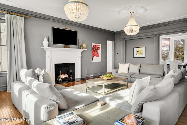 living room featuring a fireplace with flush hearth, baseboards, wood finished floors, and an inviting chandelier