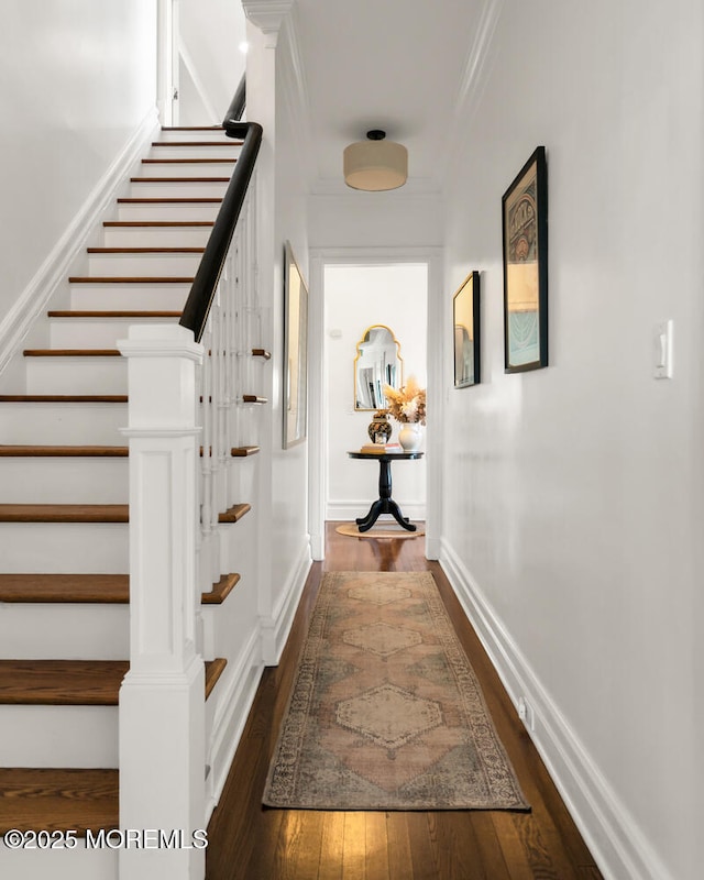 hall with crown molding, stairs, baseboards, and dark wood-style flooring