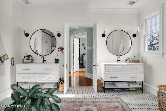 bathroom with baseboards, visible vents, ornamental molding, and two vanities