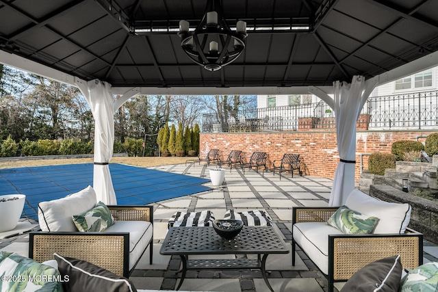 view of patio / terrace featuring a covered pool, fence, an outdoor hangout area, and a gazebo