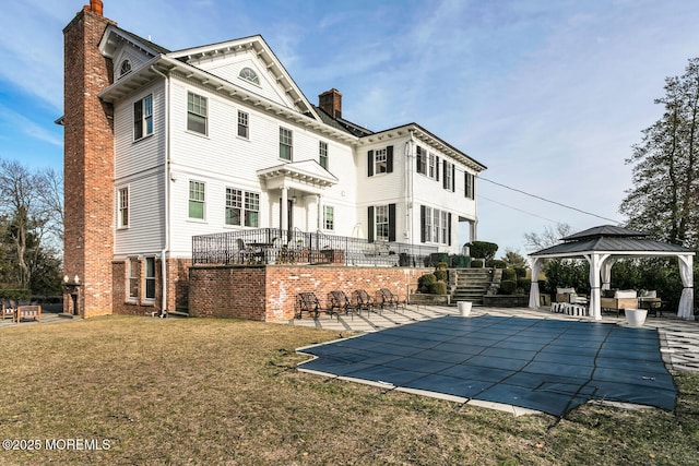 back of property with a patio area, a chimney, a lawn, and a gazebo