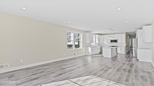 unfurnished living room featuring recessed lighting, baseboards, visible vents, and light wood finished floors