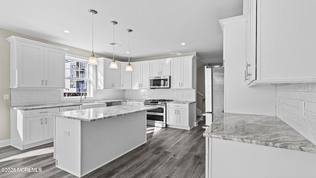 kitchen featuring stainless steel appliances, a kitchen island, white cabinets, dark wood finished floors, and decorative light fixtures