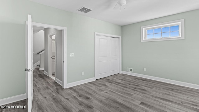 unfurnished bedroom with baseboards, a closet, visible vents, and wood finished floors