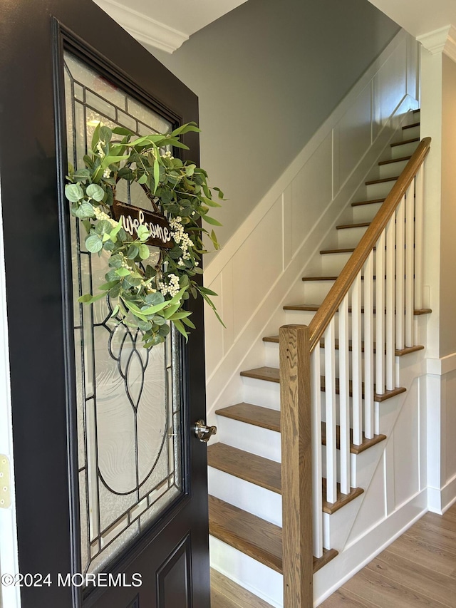 stairway with a decorative wall and wood finished floors