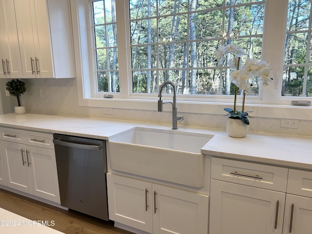 kitchen with decorative backsplash, white cabinets, dishwasher, light stone counters, and a sink