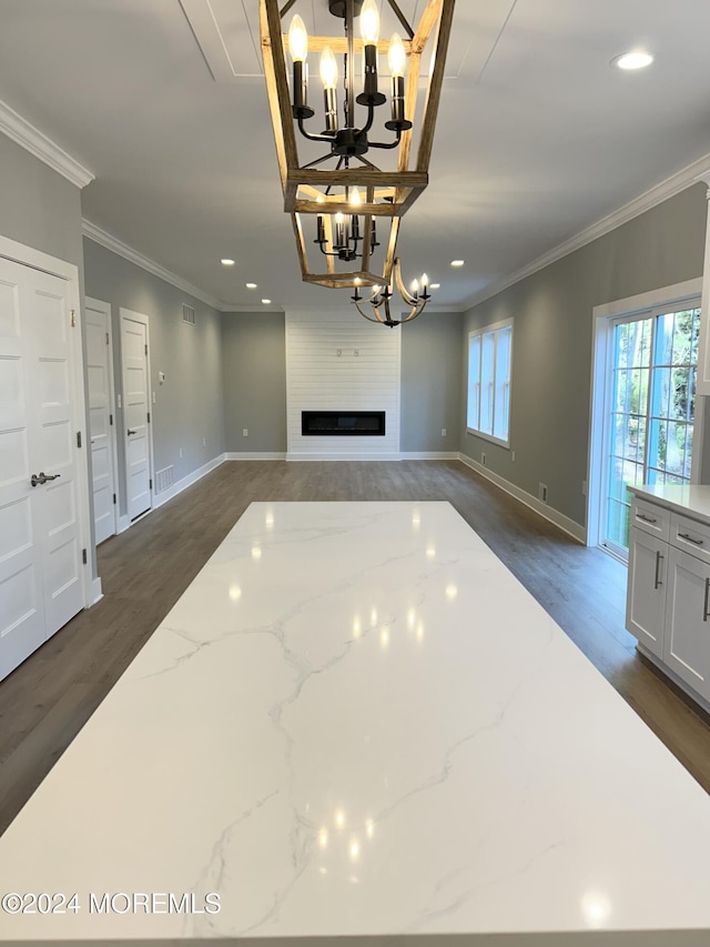 unfurnished living room featuring a large fireplace, visible vents, dark wood-style flooring, crown molding, and a chandelier