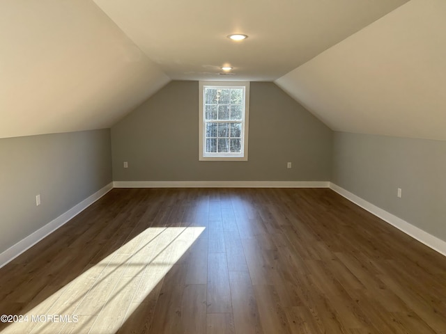 additional living space with baseboards, vaulted ceiling, and dark wood-type flooring