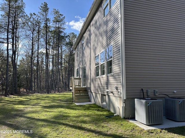 view of side of home featuring a lawn and central AC unit