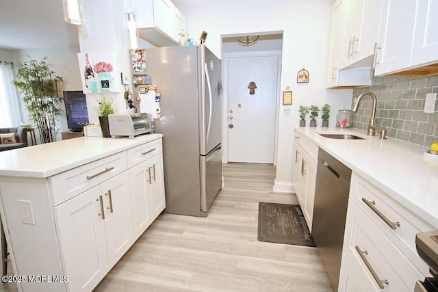 kitchen featuring white cabinets, appliances with stainless steel finishes, light countertops, and a sink