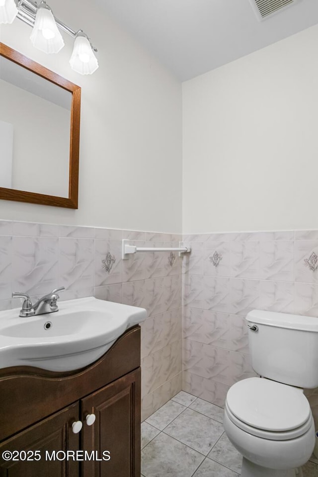 bathroom with toilet, wainscoting, visible vents, and vanity