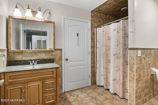 bathroom with curtained shower, a wainscoted wall, tile walls, and vanity