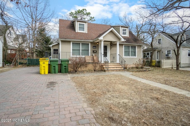 view of front of house with a shingled roof, driveway, and fence