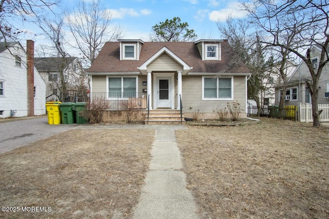 view of front of house with covered porch, roof with shingles, and fence