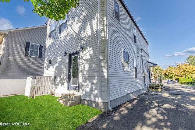 view of property exterior with a lawn and fence