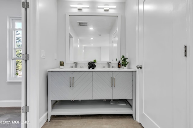 full bathroom with double vanity, wood finished floors, visible vents, and baseboards