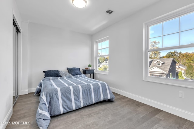 bedroom featuring wood finished floors, visible vents, and baseboards