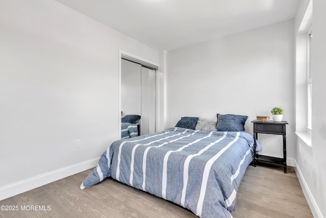 bedroom with a closet, baseboards, and wood finished floors