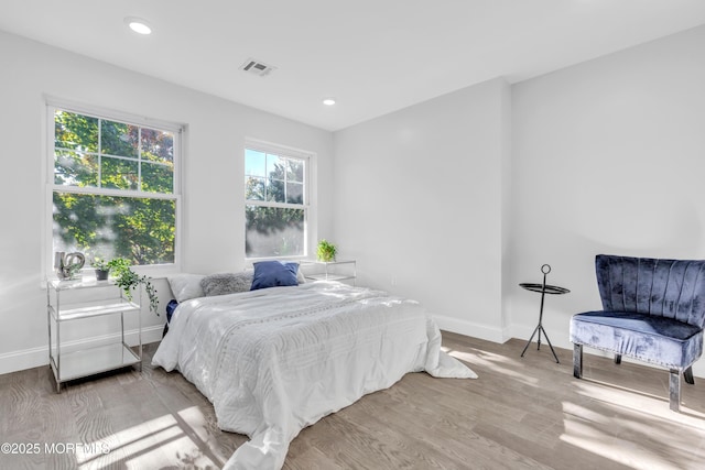 bedroom featuring baseboards, visible vents, wood finished floors, and recessed lighting