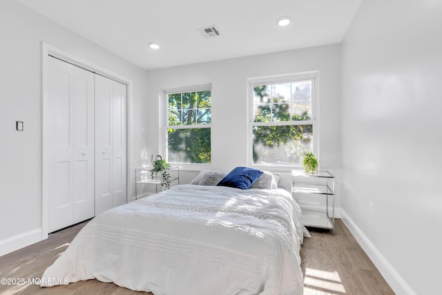 bedroom featuring visible vents, baseboards, wood finished floors, a closet, and recessed lighting