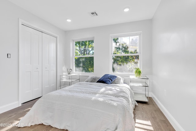 bedroom featuring a closet, visible vents, baseboards, and wood finished floors