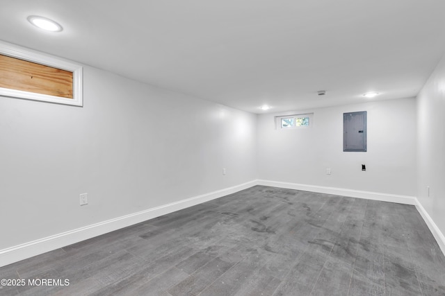 below grade area featuring dark wood-style flooring, electric panel, and baseboards