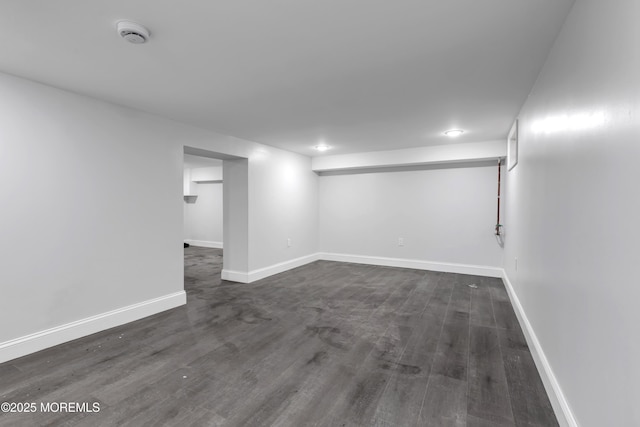 finished below grade area with dark wood-style floors and baseboards