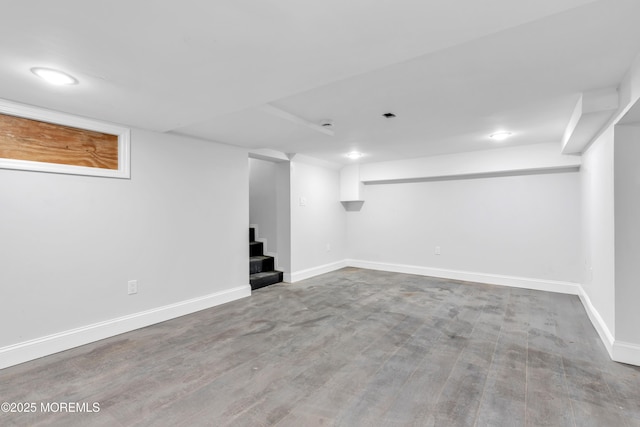 finished basement with stairway, wood finished floors, and baseboards