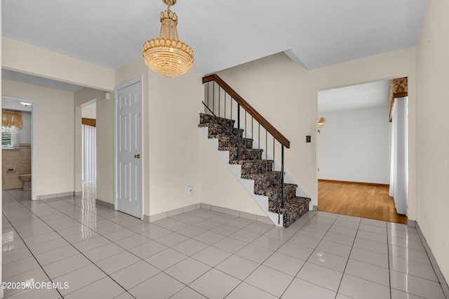 tiled foyer featuring stairway and baseboards