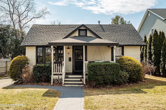 bungalow featuring a shingled roof and a front lawn