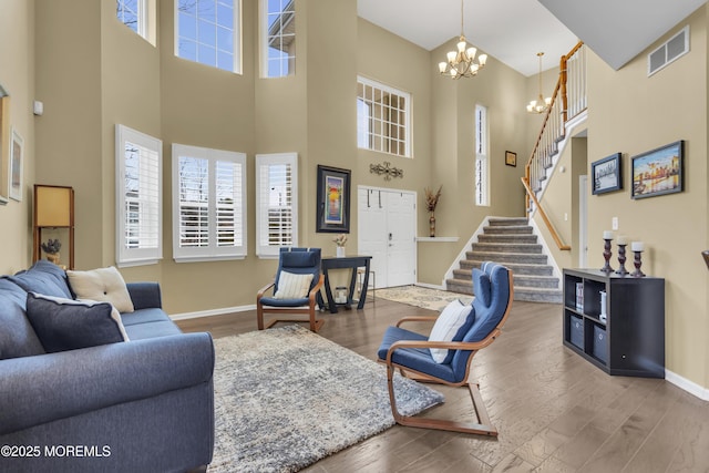 living area featuring stairs, baseboards, wood finished floors, and a notable chandelier