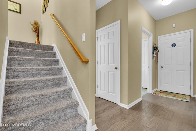 entrance foyer with stairway, wood finished floors, and baseboards