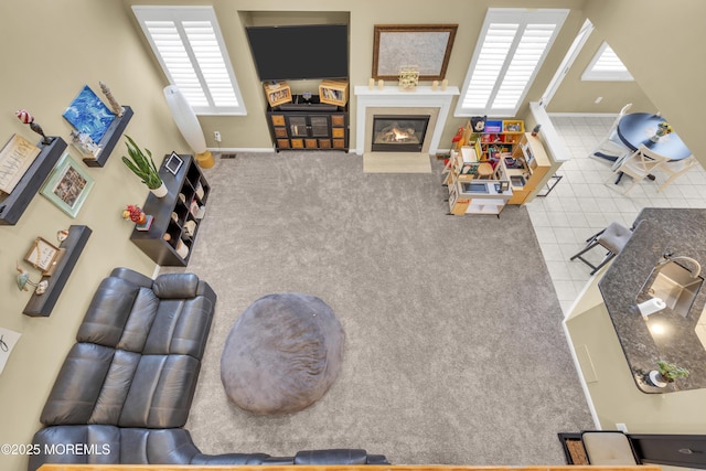 carpeted living room featuring tile patterned flooring, a glass covered fireplace, and baseboards