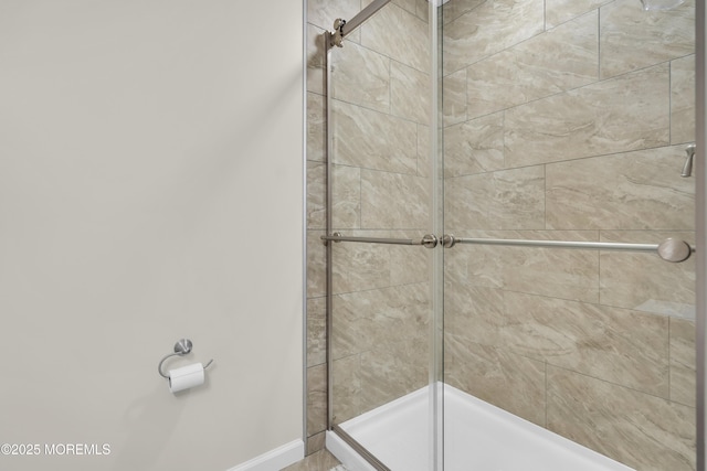 full bath featuring a shower stall and baseboards